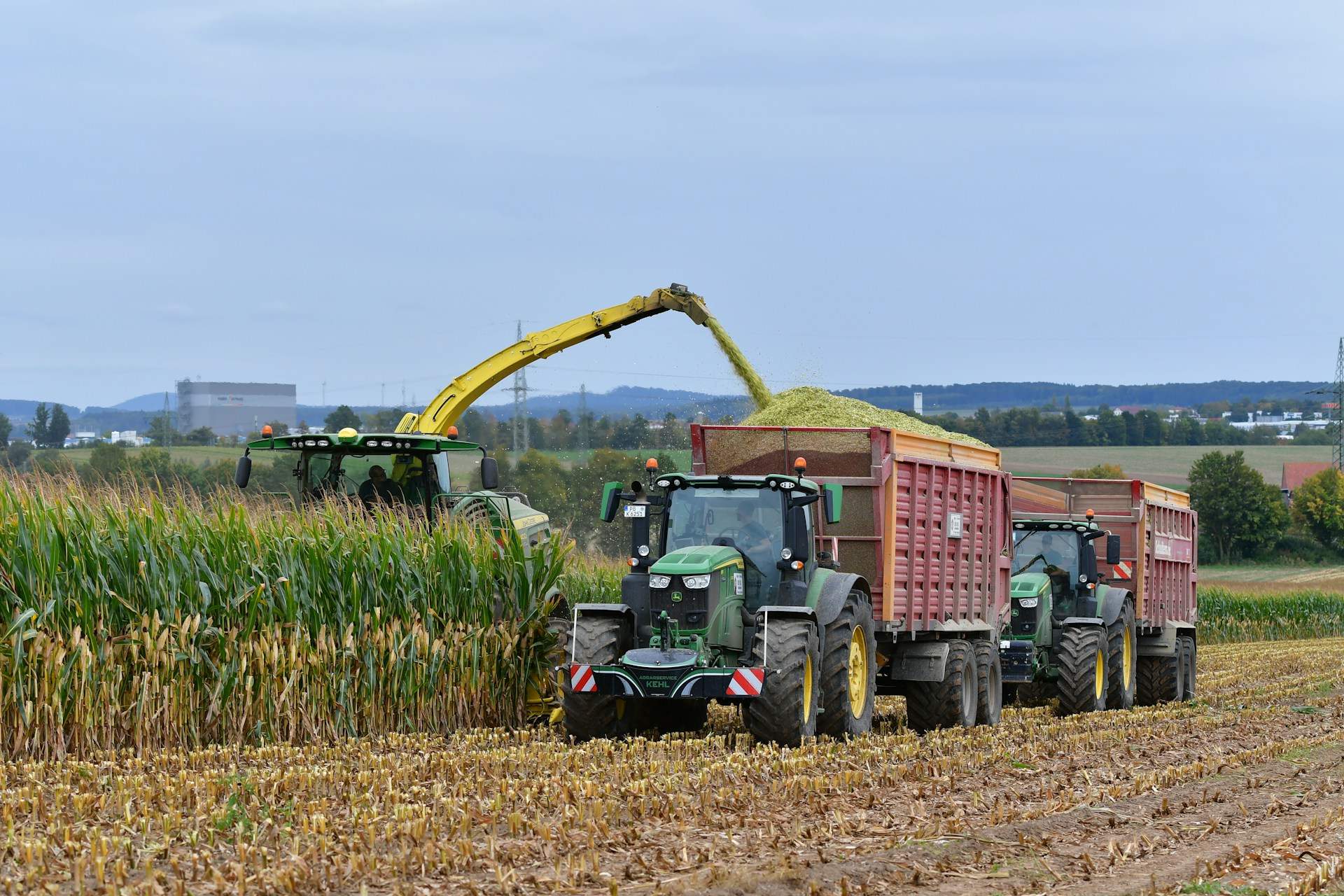 John Deere tractor filling a silage trailer at corn harvest