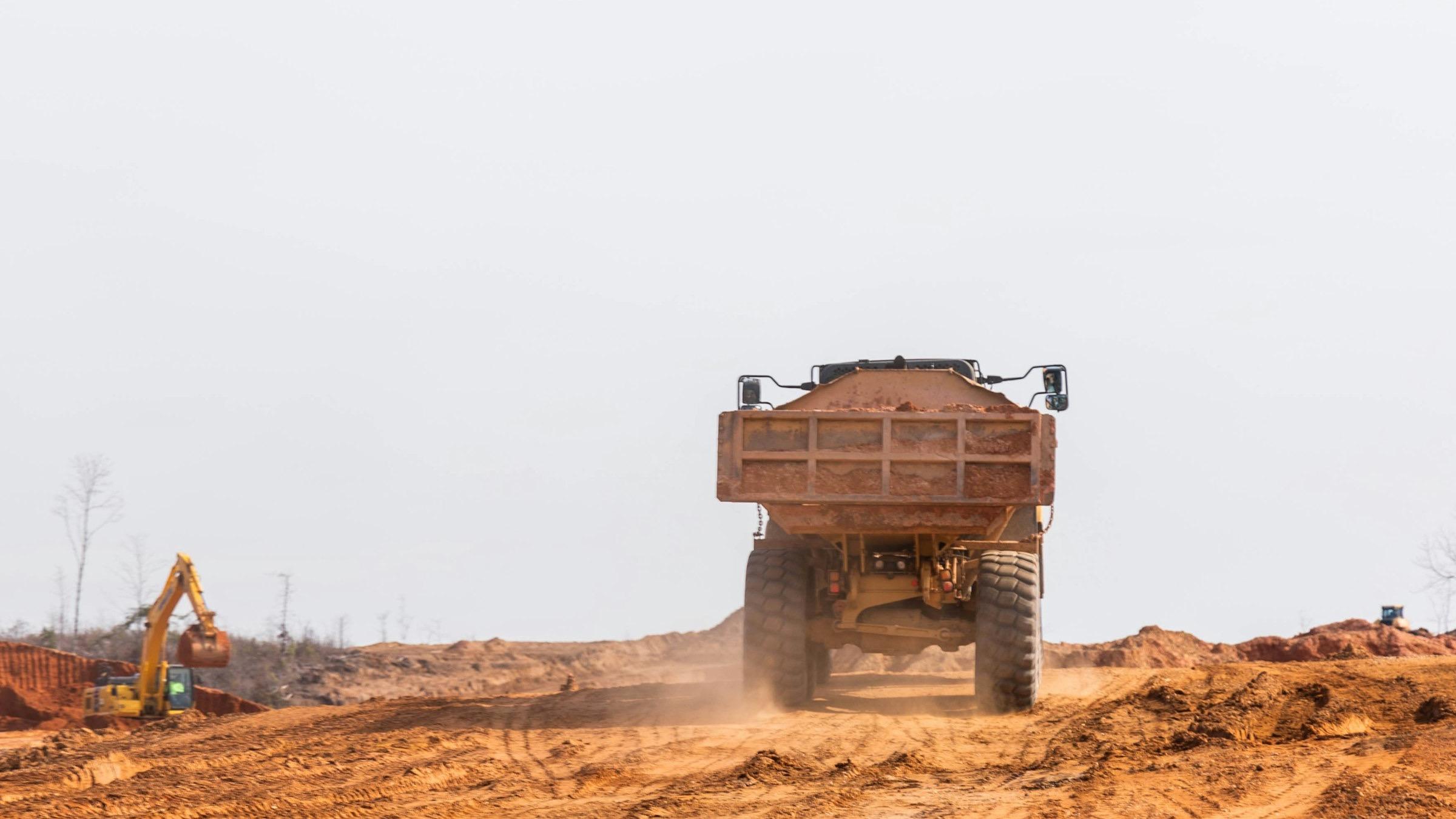Articulated dump truck hauling dirt beside an excavator