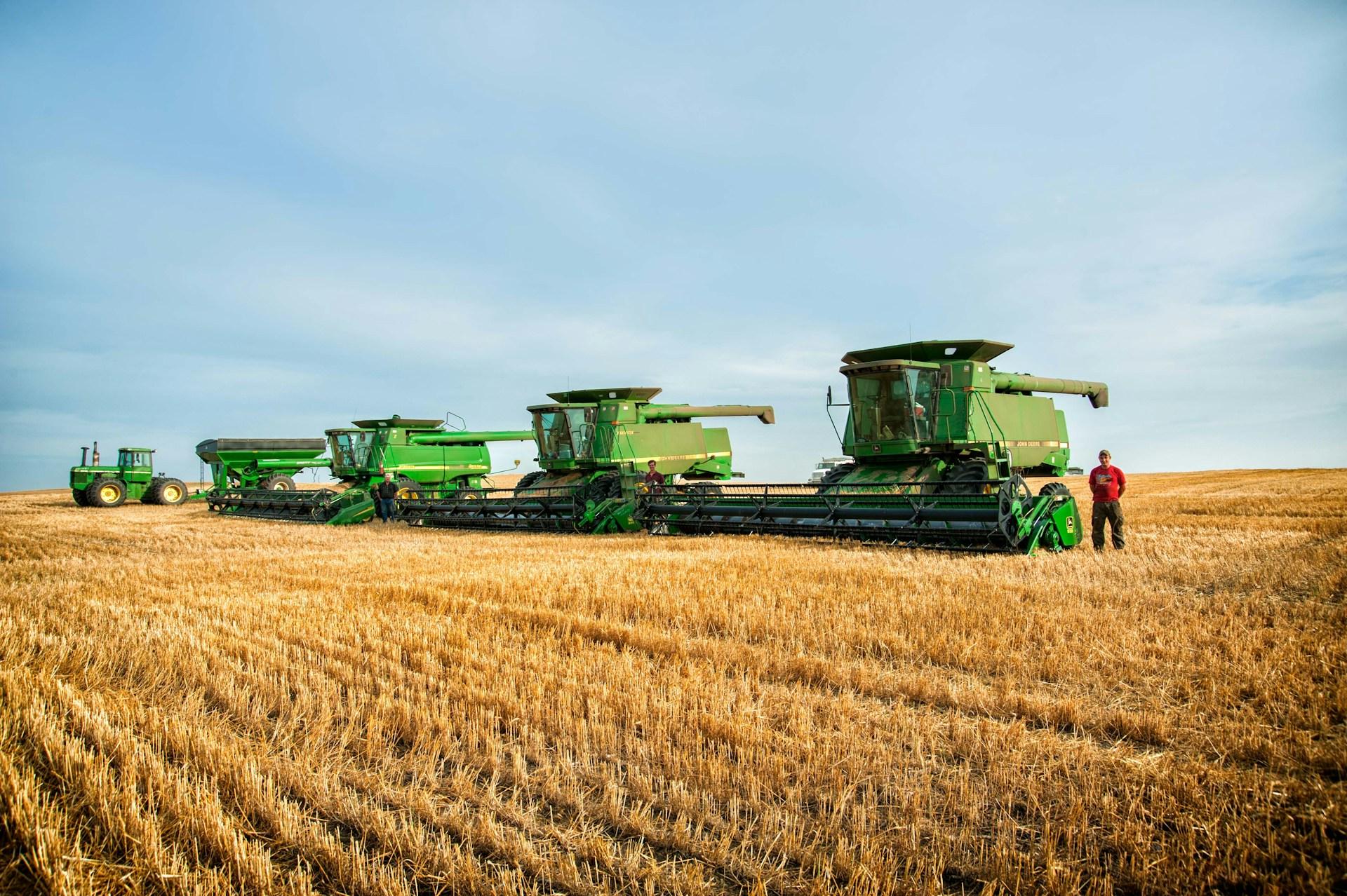 Line of John Deere combines in a harvested wheat field