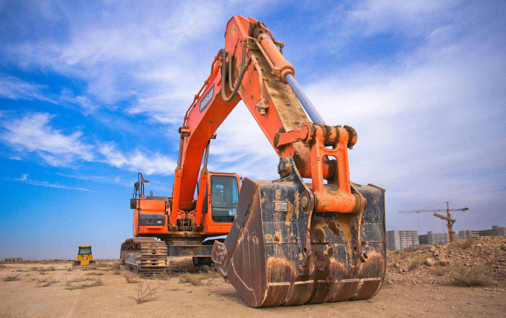 Orange excavator on a dusty construction site