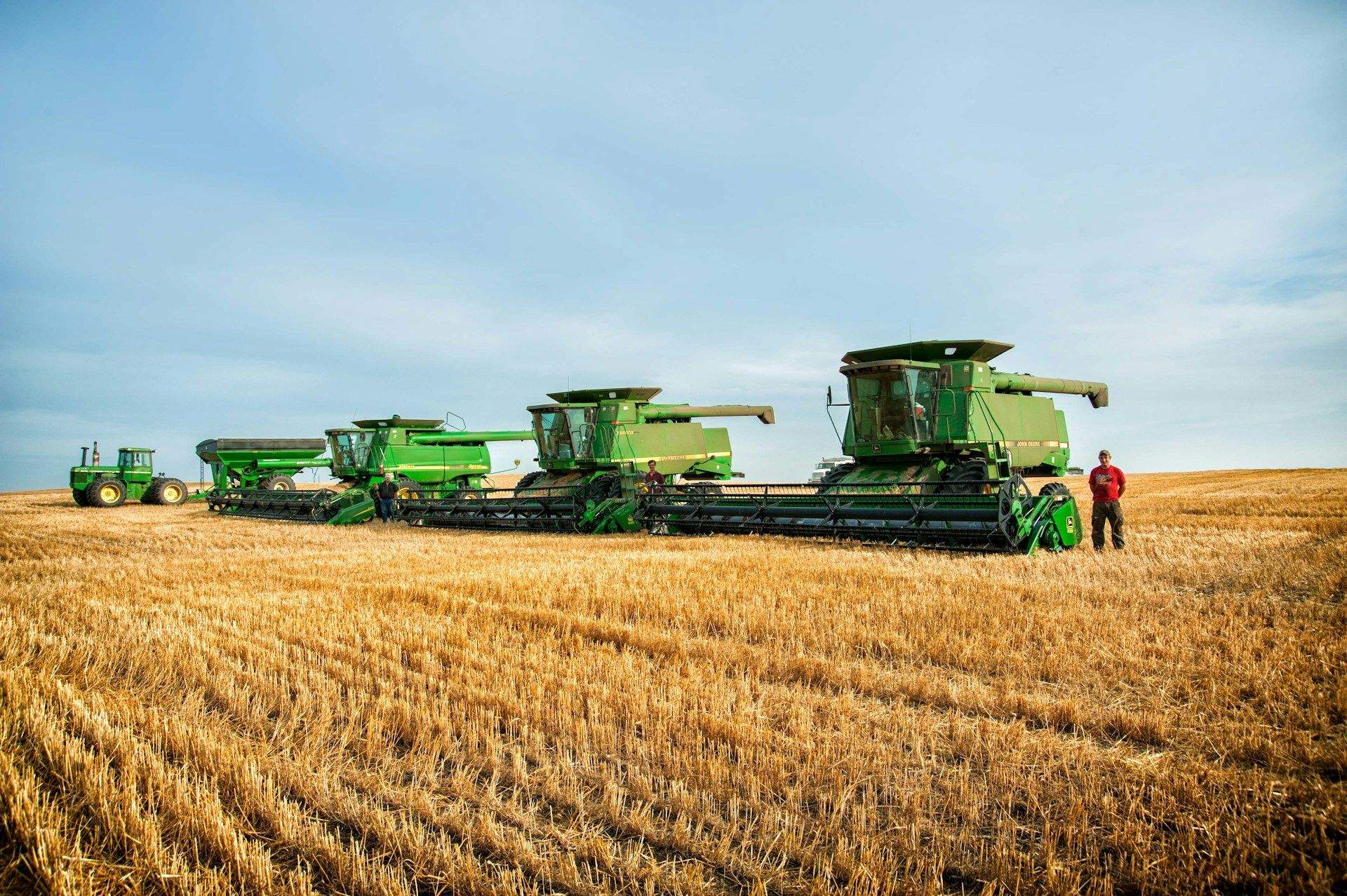 Line of John Deere combines in a harvested wheat field